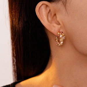 Close-up of gold C-shaped earring featuring pink strawberry quartz and delicate pearls