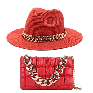 Detail of red straw jazz hat and quilted handbag set with thick gold chunky chains