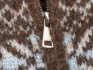 Macro detail of the silver double-zipper on a plush jacquard knit cardigan sweater