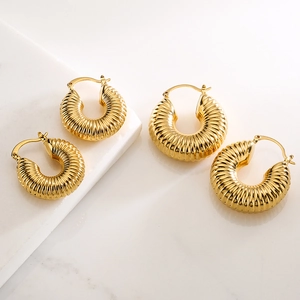 Chic gold-plated chunky hoop earrings with textured design on white marble surface
