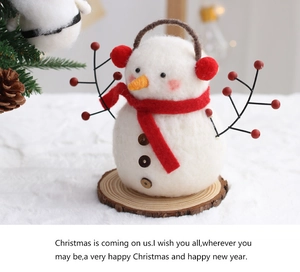 Detail of wool felt snowman ornament on a wood base with festive holiday background