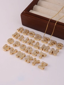 Makroaufnahme von 26 Gold-Buchstabenanhängern mit Zirkonia-Inlay und einer Goldkette
