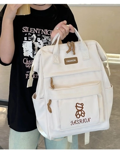 Detail of a beige Japanese-style school backpack featuring a cute bear embroidery