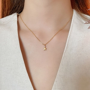 Dettaglio di una collana con ciondolo a stella dorata e zircone sul collo di una modella