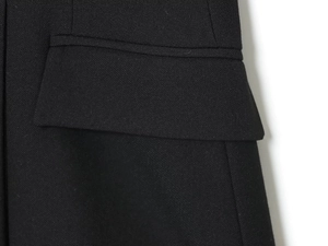 Dettaglio della trama del tessuto twill nero e della tasca con patta su un abito corto