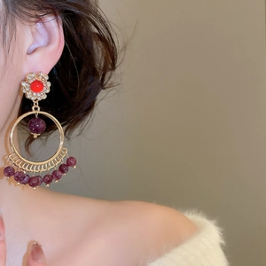 Detail of vintage gold-tone tassel earrings with red beads and crystal accents