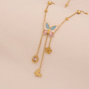 Macro shot of gold butterfly pendant with colorful enamel and dangling zircon charms