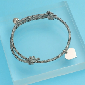 Detailed macro view of heart charm and polished ball on silver Milanese cord bracelet
