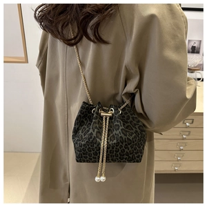 Detail of leopard print bucket bag featuring gold chain strap and pearl drawstring tassels