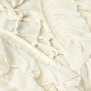 Detailed view of cream chiffon dress featuring deep V-neck and ruffled lace-up design