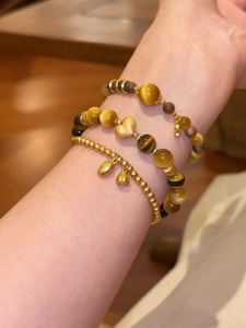 Detaillierte Ansicht des 3-teiligen Tigerauge-Armbandsets mit Herzanhänger am Handgelenk