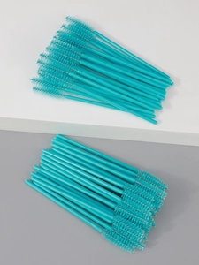Detail of disposable turquoise eyelash spoolies arranged neatly on a grey and white platform