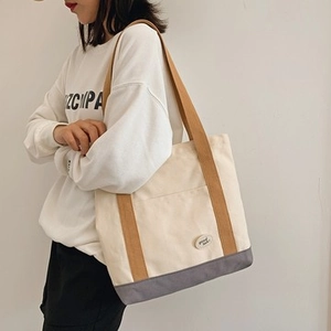 Detail of canvas tote bag with good luck patch and contrasting grey bottom panel