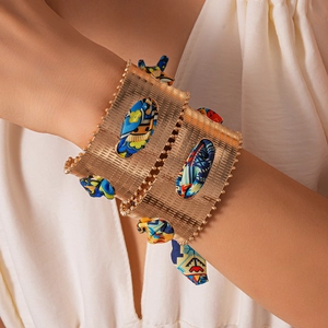 Detail of gold metal cuff bracelet with colorful silk scarf weaving for bohemian style