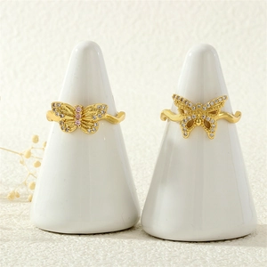 Detail of 18K gold butterfly rings with sparkling zircon inlay and wavy metal band