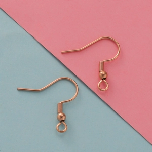 Detailed view of rose gold earring hooks with spring beads on a dual-tone background