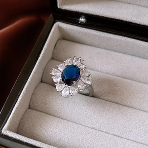 Detail of sunflower style ring with oval blue gemstone and cubic zirconia in a jewelry box