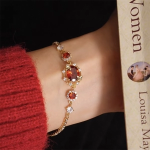 Detailed close-up of 18K gold plated bracelet with red oval gems and white zircon stones