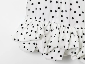 Vue détaillée d'une robe blanche à pois avec ourlet à volants et texture en mousseline