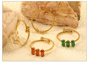 Detailed view of adjustable golden rope rings with colorful zircon stones on natural rocks