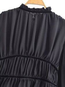 Detail of black chiffon top featuring ruffled neckline and velvet trim on back