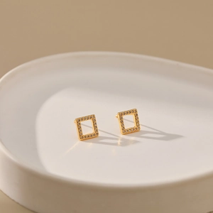 Close-up of geometric square hollow earrings with 18K gold plating and pave-set zircons