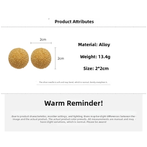 Close-up of golden spherical stud earrings with textured finish and silver pin details