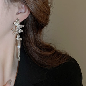 Close-up of elegant silver butterfly tassel earrings with sparkling rhinestones on a model