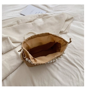 Top view of woven beach bag showing interior beige lining and elegant pearl handle detail