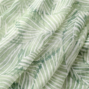 Macro view of light bohemian scarf fabric featuring green and white palm leaf patterns