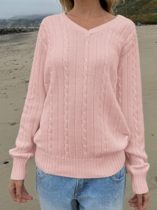 Detailed knit texture and ribbed cuffs of women's pink V-neck cable sweater on beach