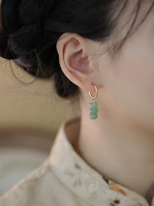 Macro view of minimalist gold earrings with three cascading green aventurine beads