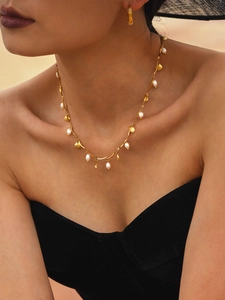 Detail shot of gold shell and freshwater pearl necklace set on a female model