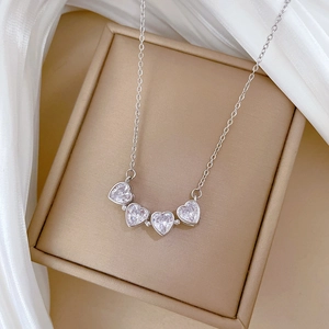 Detail of silver clover necklace with five heart-shaped crystals on a jewelry box