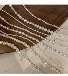 Detailed comparison of eight natural freshwater pearl shapes and sizes on textured fabric