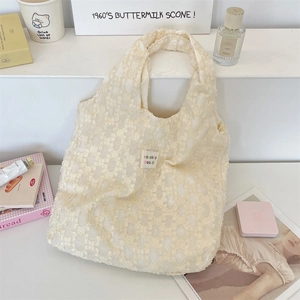 Detailed macro of creamy white lace handbag with 3D crochet flowers and brand label