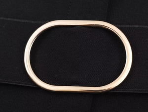 Detailed macro view of an elastic black waist belt featuring a polished gold oval buckle