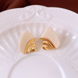 Gros plan détaillé de boucles d'oreilles géométriques en résine et métal doré chic