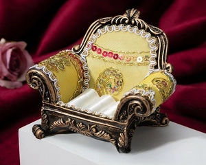 Macro view of vintage sofa-style ring holder with ornate bronze frame and yellow fabric