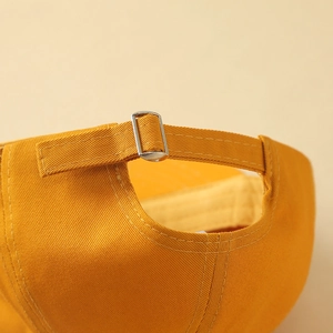 Detailed close-up showing the adjustable metal buckle on back of yellow cotton baseball cap
