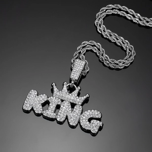 Macro shot of silver KING pendant with crown and iced-out crystals on rope chain