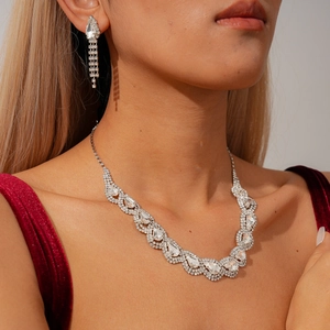 Detail of luxury teardrop crystal necklace and earring set on model in velvet dress