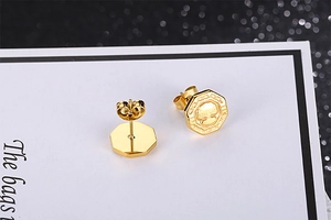 Vue macro de boucles d'oreilles octogonales dorées avec relief d'arbre de vie