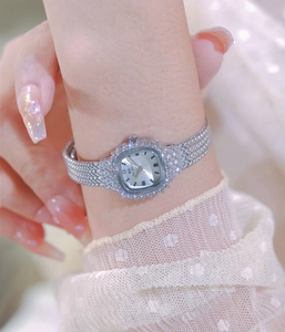 Close-up of silver square watch with rhinestone bezel and metal mesh strap on wrist
