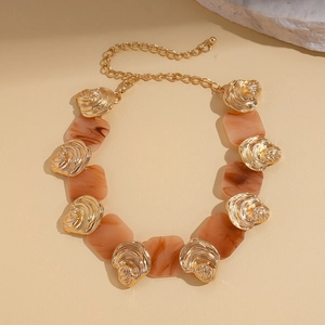 Detail view of resin square pendant and shell textured metal on golden necklace