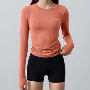 Coral long-sleeve yoga top with thumbholes and black fitness shorts for women