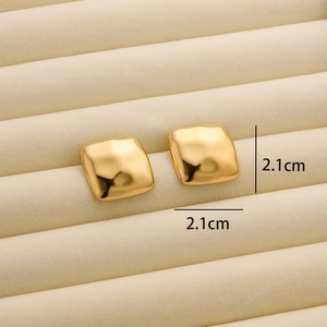 Detail of 18K gold-plated titanium earrings with irregular hammered texture on velvet pad