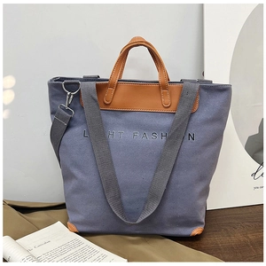 Detail of grey canvas tote bag with brown leather handles and LIGHT FASHION logo