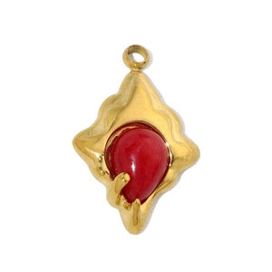 Macro shot of gold textured lava frame with red teardrop stone pendant detail