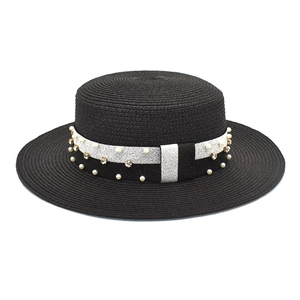 Detail of black straw boater hat with pearl and rhinestone embellishments on ribbon